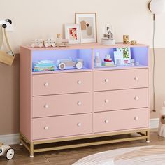 a baby's room with pink furniture and pictures on the wall above it, along with toys