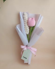 a pink crocheted teddy bear wrapped in white paper and tied with a ribbon