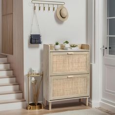 an entryway with a wicker chest and hat rack on the wall next to stairs