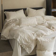 an unmade bed with white linens and ruffled edges in a bedroom setting