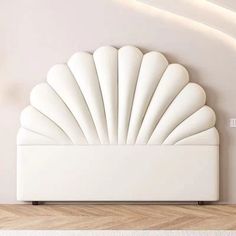 a large white shell bed sitting on top of a wooden floor next to a wall