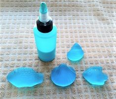 three blue sea shells and a bottle of lotion sitting on a mat with the lid open