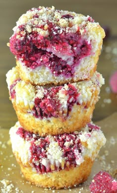 three raspberry muffins stacked on top of each other with powdered sugar