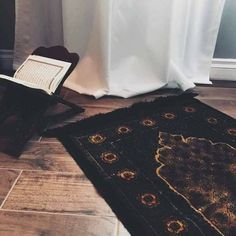 an open book sitting on top of a wooden floor next to a chair and rug