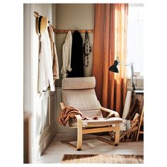 a chair sitting in front of a window next to a wall mounted coat rack with clothes hanging on it