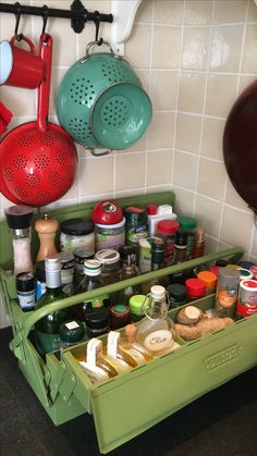 a green cabinet with pots and pans hanging on the wall next to other kitchen utensils