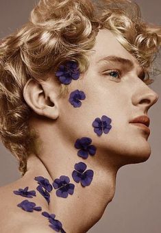 a man with flowers painted on his face and neck, looking to the left side