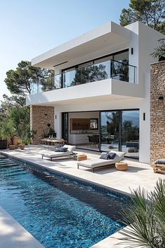 a modern house with a swimming pool in the foreground and patio furniture on the other side