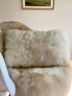 a white chair with a fur cushion on it's back and armrests