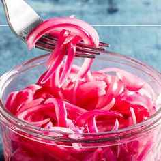 red onions being cut into small pieces in a glass bowl with a fork sticking out of it