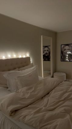 a bed with white sheets and pillows in a bedroom next to two pictures on the wall