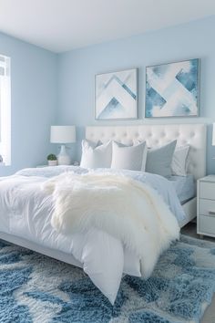 a bedroom with blue walls, white bedding and two pictures on the wall above it