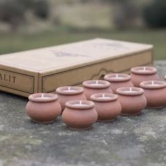 there are many small pink candles in front of a box on the stone table with it's lid open