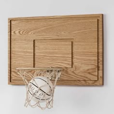 a basketball going through the hoop on a wooden wall mounted basketball board with an official ball in it