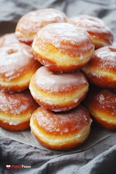 a pile of glazed donuts sitting on top of each other in front of a black cloth