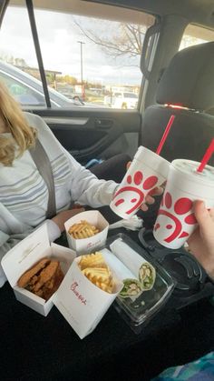 a woman sitting in the back seat of a car with food