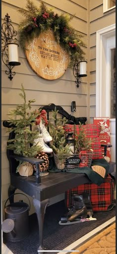 a bench with christmas decorations on it sitting in front of a door and wreaths hanging from the wall