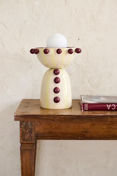 an egg sitting on top of a table next to a book and a vase filled with eggs