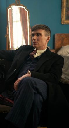 a man sitting on top of a couch wearing a suit and bow tie in front of a mirror