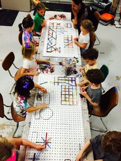 a group of children sitting at a table working on crafts