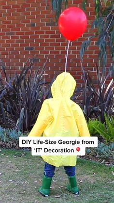 a small child wearing a raincoat and holding a red balloon with the words diy life - size george from it's decoration