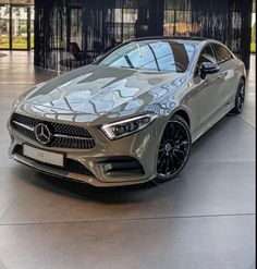 the mercedes cla is parked in front of a black wall and some windows with curtains behind it