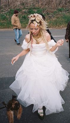 a woman in a white dress is walking her dog