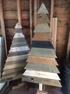 several wooden christmas trees sitting in a room with wood planks on the walls and floor