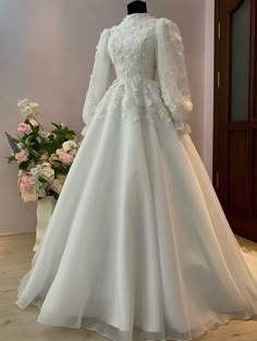 a white wedding dress with long sleeves on display