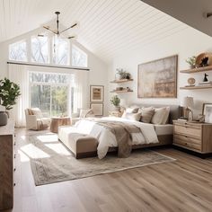 a large bedroom with white walls and wooden flooring, along with windows that look out onto the woods