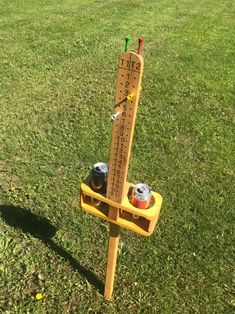 a wooden pole with two cups on it in the grass next to a measuring ruler