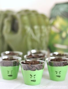 small cups filled with dirt and chocolate chips on top of a white table next to a green bag