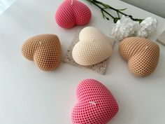 four heart shaped cushions sitting on top of a white table next to flowers and a vase