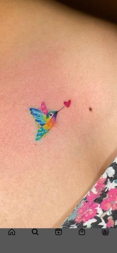 a small hummingbird tattoo on the back of a woman's shoulder and chest