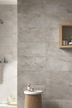 a bathroom with grey tiles and wooden shelves