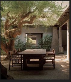 a table and chairs under a tree in the middle of a courtyard with stone walls