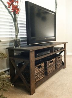 a flat screen tv sitting on top of a wooden stand next to a vase with flowers