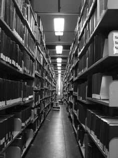 an aisle in a library filled with lots of books and binders on the shelves