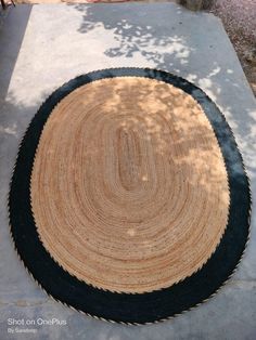 a black and tan rug sitting on top of a cement floor next to a tree