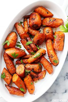 roasted carrots with herbs in a white bowl on a marble countertop, ready to be eaten