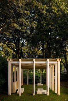 a group of white benches sitting in the middle of a lush green park next to trees