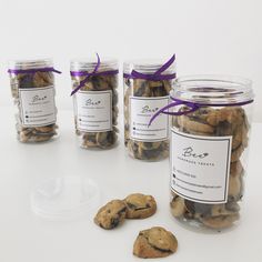 four jars filled with cookies and chocolate chip cookies next to each other on a table