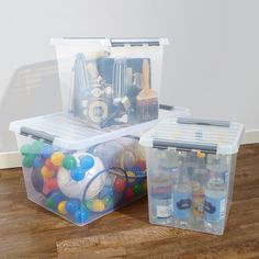 two plastic storage containers filled with toys on top of a wooden floor