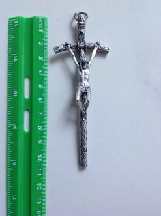 a crucifix is next to a ruler on a white surface with a green handle