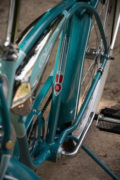 the front wheel of a blue bicycle with red and white stickers on it's spokes