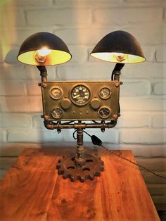 two lamps sitting on top of a wooden table next to a clock and gear wheel