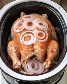 a whole chicken with onions in the middle of it's body inside an electric pressure cooker