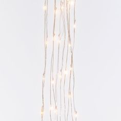 a string of lights hanging from the ceiling in front of a white wall with no one on it