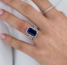 a woman's hand wearing a ring with an emerald and diamond set in it