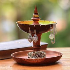 a wooden stand with jewelry on it and a book in the backgroung